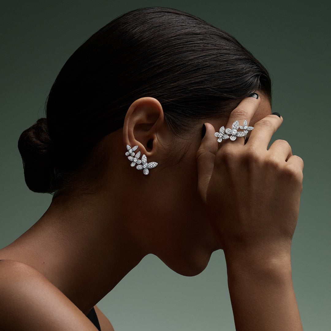 Close-up of a woman wearing Arvelle diamond butterfly ear climbers and a matching diamond butterfly ring